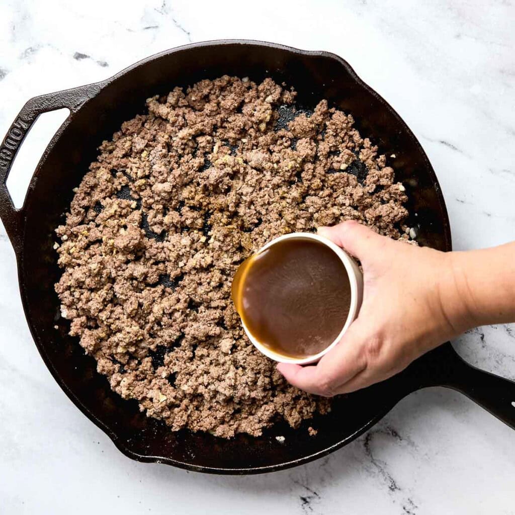 Adding beef broth to Cowboy Casserole.