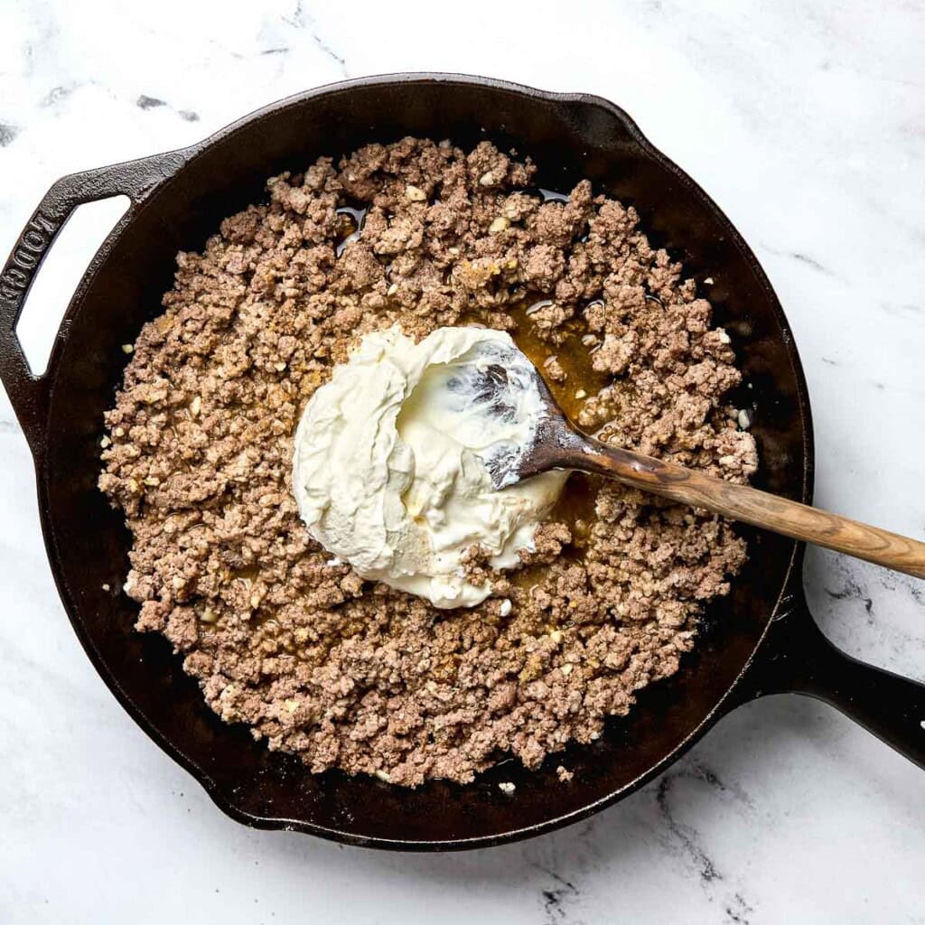 Adding sour cream to Cowboy Casserole recipe.