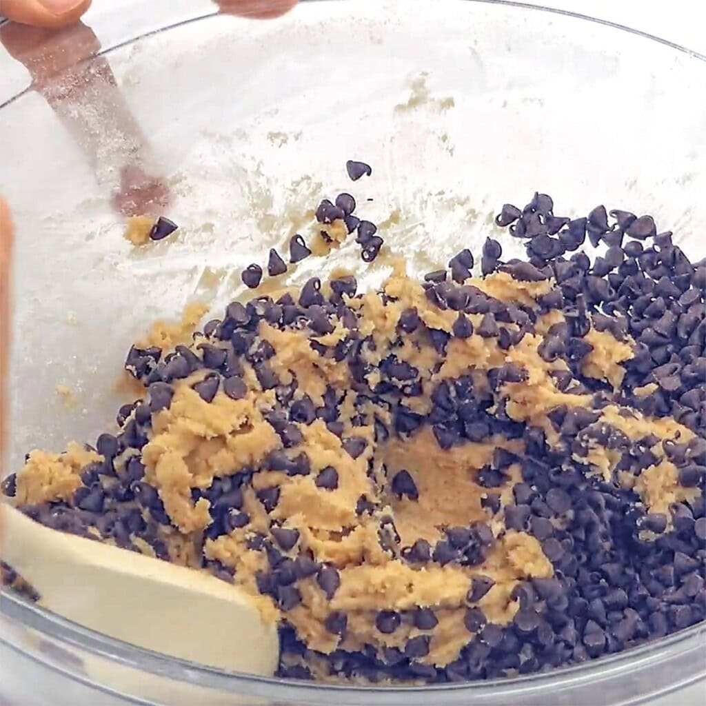 Mixing in chocolate chips with wooden spoon for Whole Wheat Chocolate Chip Cookies.